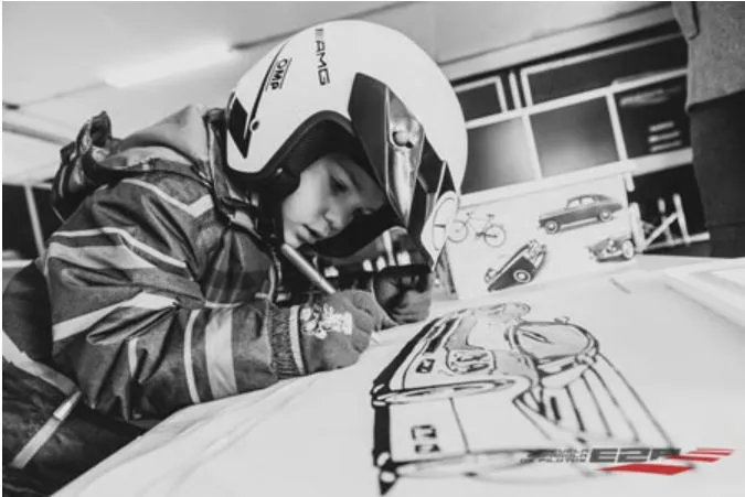 Niño con casco de piloto dibujando un coche de carreras